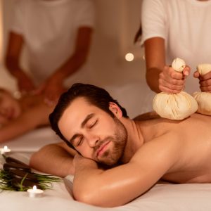 Couple,Relaxing,During,Herbal,Back,Massage,With,Aromatic,Bags,And